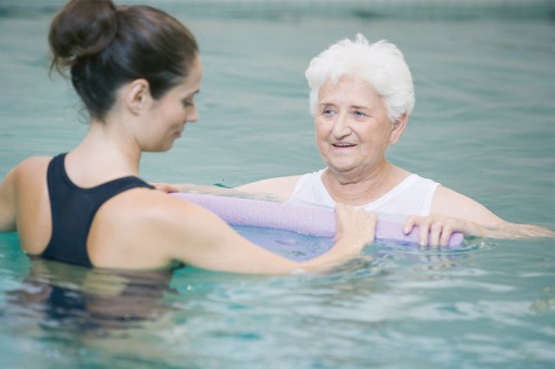zwemmende oudere en instructrice